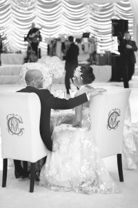 bride and groom sitting in monogrammed bridal chairs