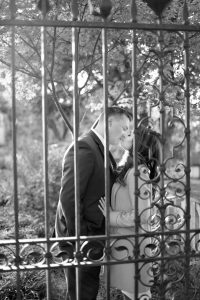 engaged couple kissing behind an iron gate