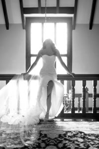 Sexy and tasteful black and white image of a bride backlit in front of a large picture window
